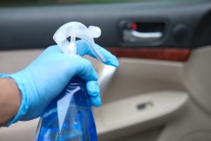 hand in gloves holding spray bottle cleaning car door ,