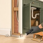 Illustration of a careful home inspection near a baseboard and under-sink cabinet for possible mouse signs.